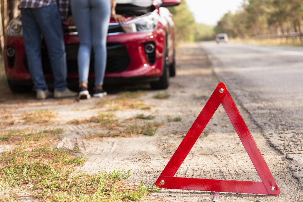 signo de triangulo rojo en la carretera por problemas con el automovil mientras viaja
